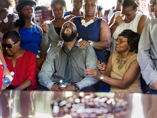 Michael Brown Sr. (center), surrounding by family at the grave site where his son was laid to rest.